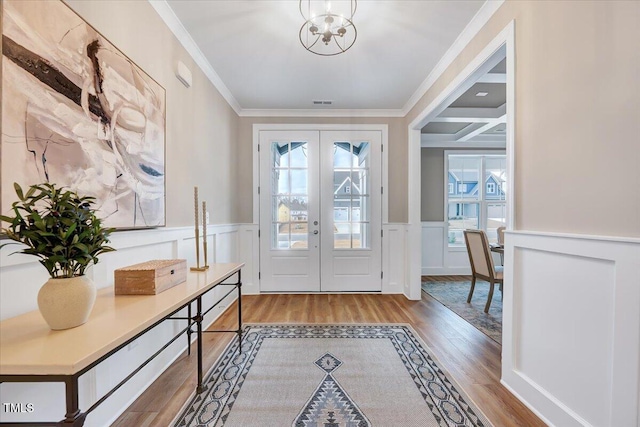 doorway to outside featuring french doors, ornamental molding, light hardwood / wood-style flooring, and a notable chandelier