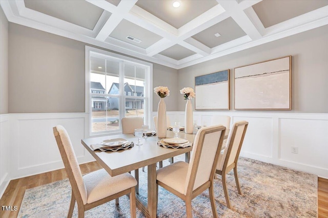 dining area featuring beamed ceiling, coffered ceiling, and light hardwood / wood-style flooring