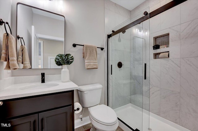 bathroom featuring a shower with door, vanity, and toilet