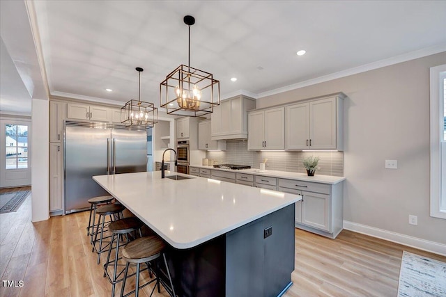 kitchen featuring a kitchen bar, ornamental molding, stainless steel appliances, and a center island with sink