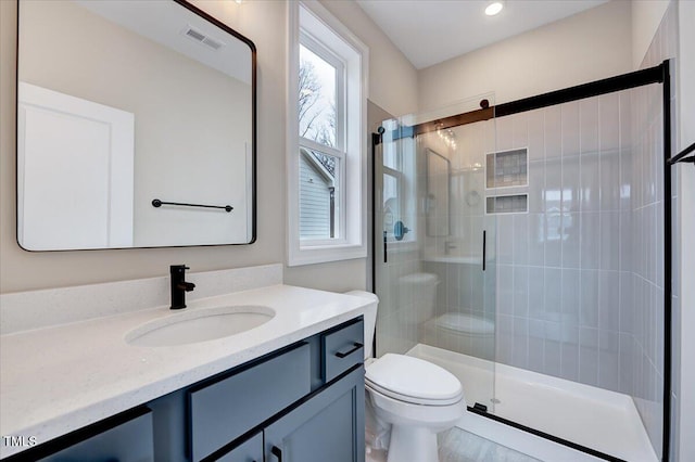 bathroom featuring vanity, walk in shower, and toilet