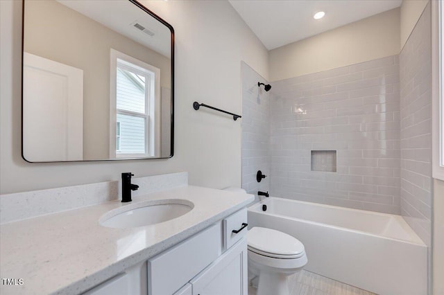 full bathroom with vanity, tiled shower / bath combo, and toilet