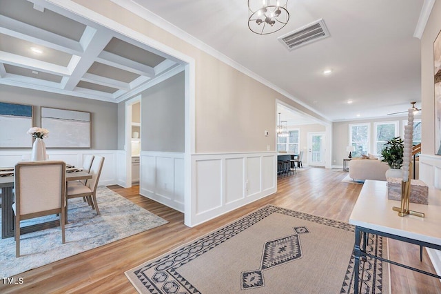 interior space with beamed ceiling, coffered ceiling, light wood-type flooring, and an inviting chandelier