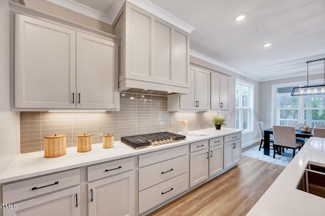 kitchen featuring stainless steel gas stovetop, crown molding, pendant lighting, and backsplash