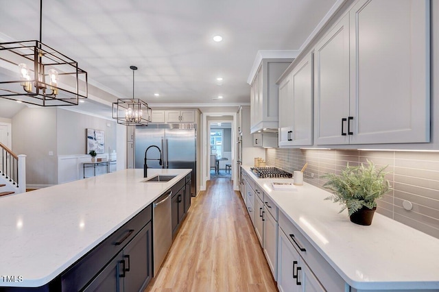 kitchen with appliances with stainless steel finishes, tasteful backsplash, hanging light fixtures, a kitchen island with sink, and crown molding