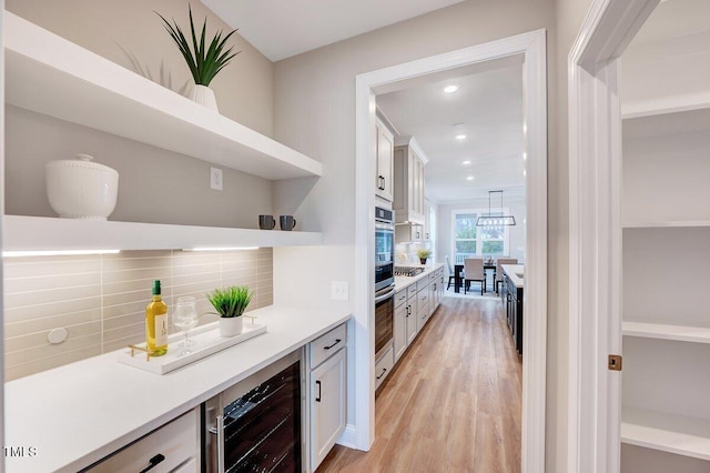 bar with white cabinetry, beverage cooler, tasteful backsplash, and light hardwood / wood-style flooring