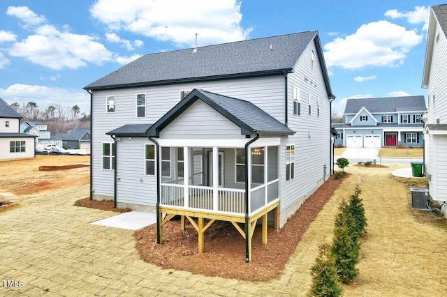 rear view of house featuring central AC and a sunroom