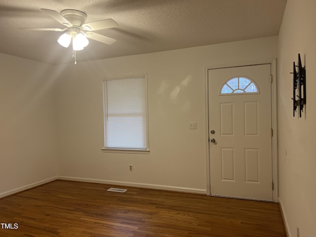 entrance foyer with ceiling fan, dark wood-type flooring, and a textured ceiling