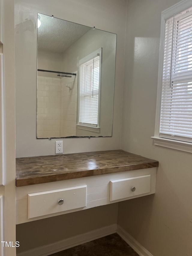 bathroom with a healthy amount of sunlight, a textured ceiling, and vanity