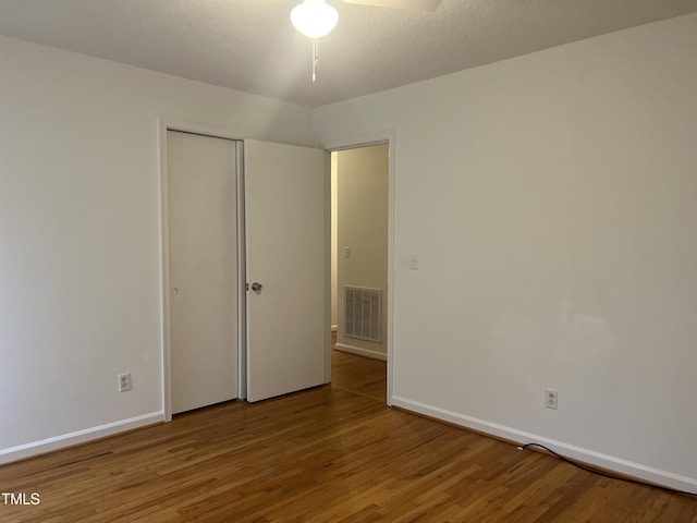 unfurnished bedroom featuring a closet, visible vents, baseboards, and wood finished floors