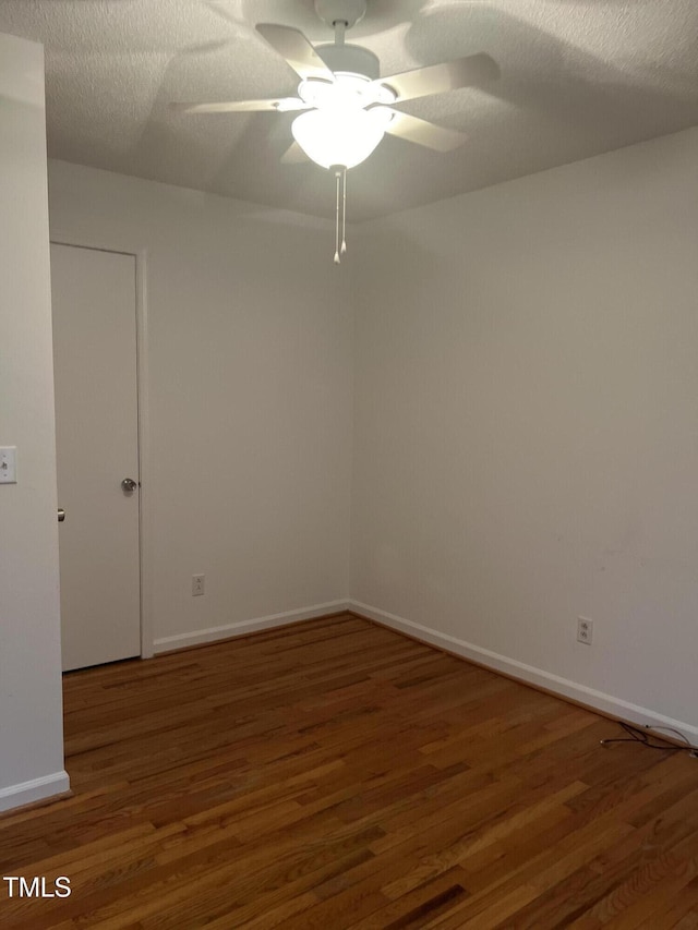 empty room featuring a ceiling fan, a textured ceiling, baseboards, and wood finished floors