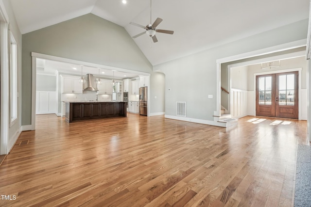 unfurnished living room with french doors, ceiling fan, high vaulted ceiling, and light hardwood / wood-style floors