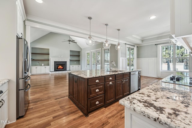 kitchen featuring appliances with stainless steel finishes, an island with sink, sink, white cabinets, and dark brown cabinetry