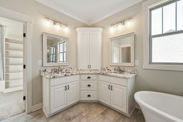 bathroom featuring a bathing tub, ornamental molding, and vanity