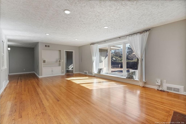 unfurnished living room with a textured ceiling and light wood-type flooring