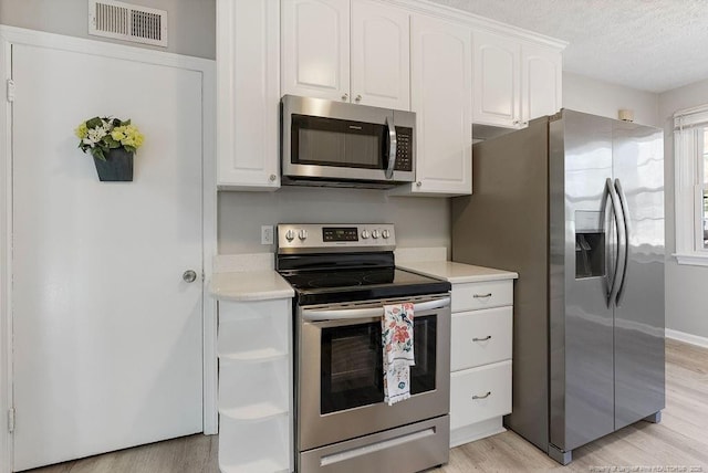 kitchen with white cabinetry, appliances with stainless steel finishes, a textured ceiling, and light wood-type flooring