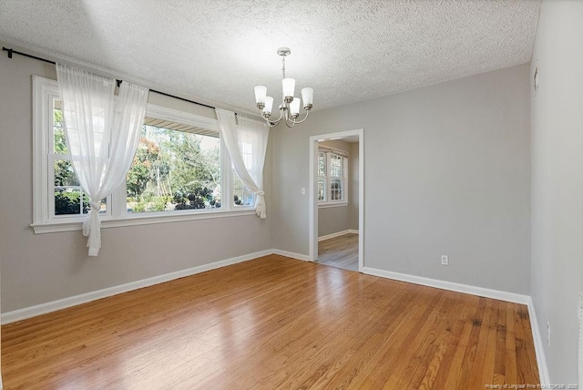 empty room featuring hardwood / wood-style floors, a textured ceiling, and a chandelier