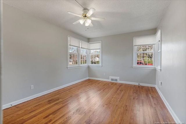 spare room featuring hardwood / wood-style flooring, plenty of natural light, a textured ceiling, and ceiling fan