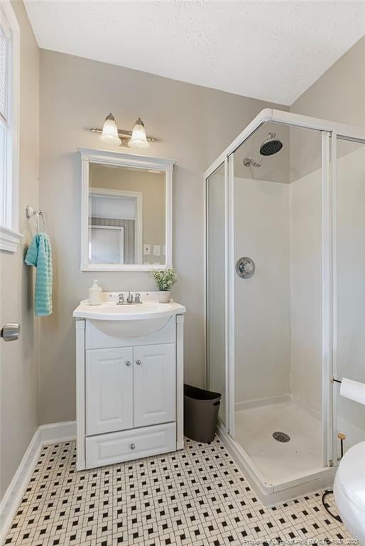 bathroom with tile patterned floors, toilet, a textured ceiling, vanity, and a shower with door