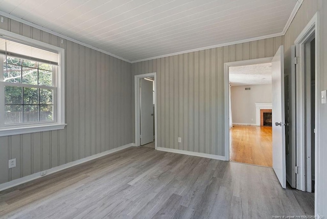 unfurnished room with crown molding, a fireplace, and light hardwood / wood-style floors