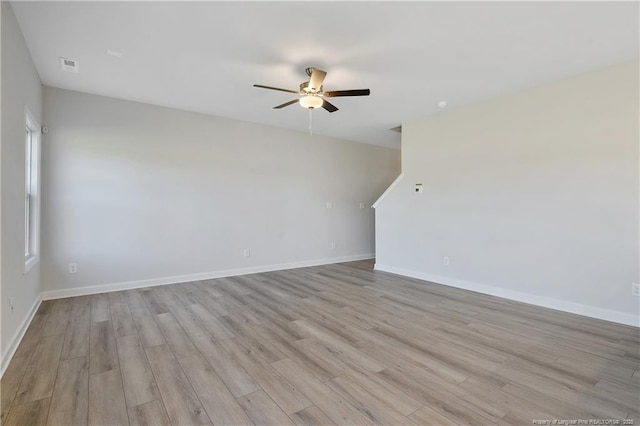 spare room with a ceiling fan, baseboards, visible vents, and light wood finished floors