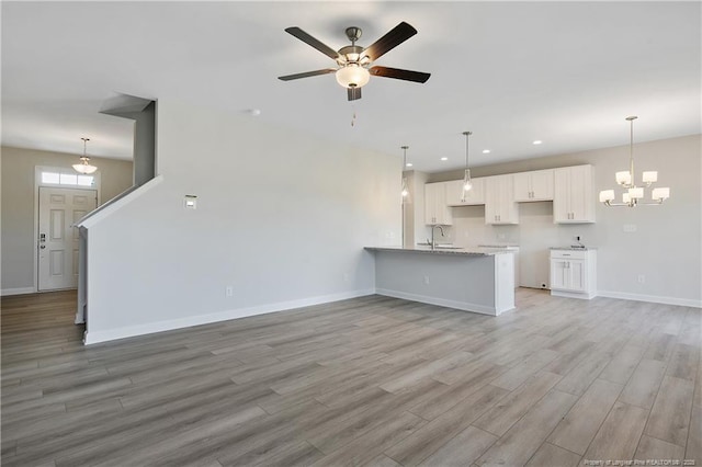 unfurnished living room with recessed lighting, light wood-style flooring, a sink, baseboards, and ceiling fan with notable chandelier