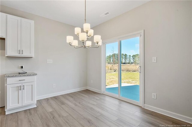 unfurnished dining area with light wood-type flooring, an inviting chandelier, baseboards, and visible vents