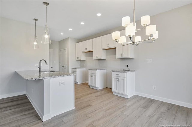 kitchen featuring light stone counters, a sink, and white cabinets