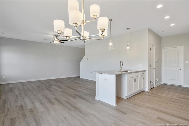 kitchen featuring light wood finished floors, recessed lighting, a sink, and white cabinets