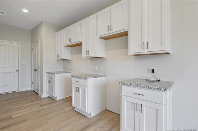 kitchen featuring visible vents, white cabinets, light stone counters, light wood-style floors, and recessed lighting