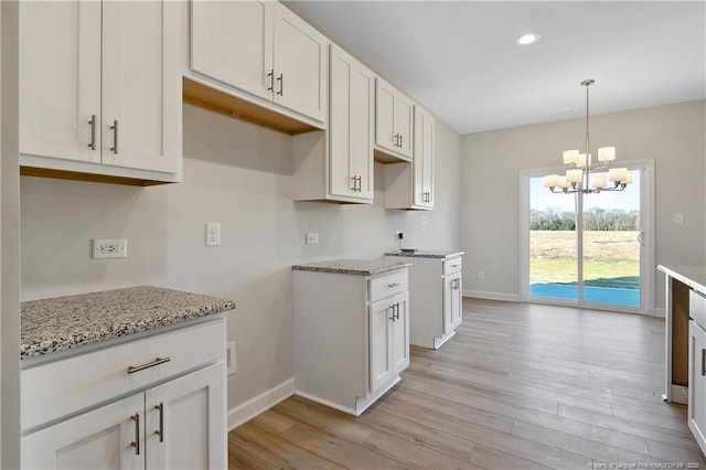kitchen with light wood finished floors, light stone counters, and a chandelier