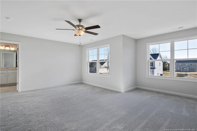 empty room featuring baseboards, ceiling fan, visible vents, and light colored carpet