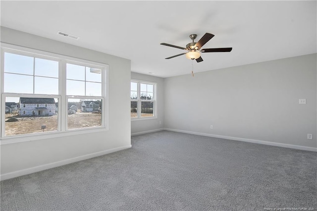 carpeted spare room with a ceiling fan, visible vents, and baseboards