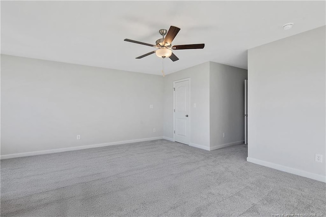 carpeted spare room featuring ceiling fan and baseboards