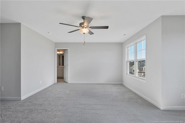 carpeted spare room with a ceiling fan and baseboards