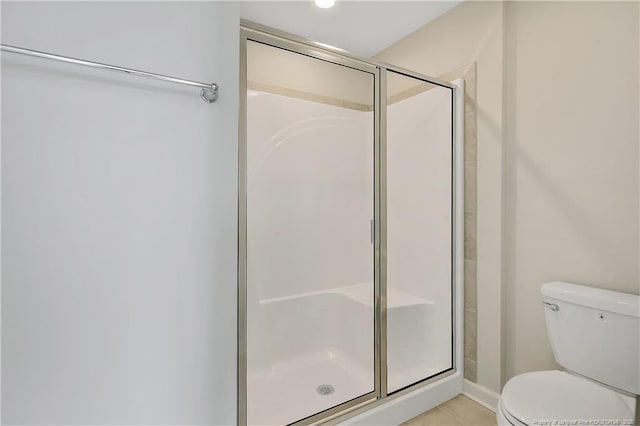 bathroom with tile patterned flooring, a shower stall, and toilet