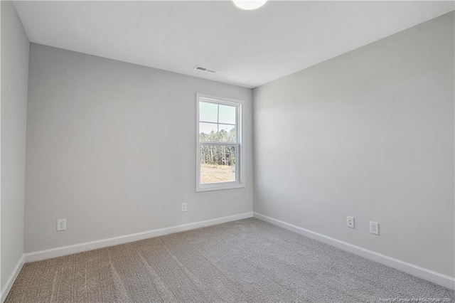 carpeted spare room with visible vents and baseboards