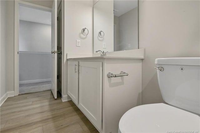 bathroom featuring vanity, wood finished floors, toilet, and baseboards