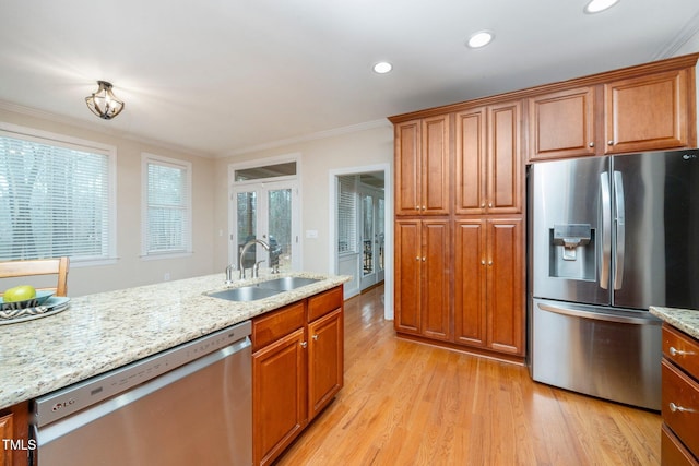 kitchen featuring light stone counters, sink, crown molding, and appliances with stainless steel finishes