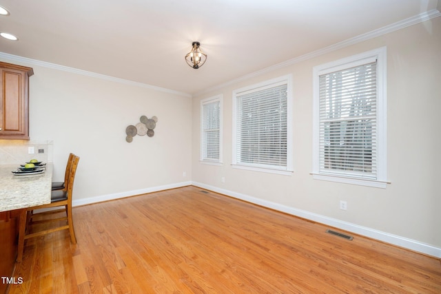 unfurnished dining area with crown molding and light hardwood / wood-style floors