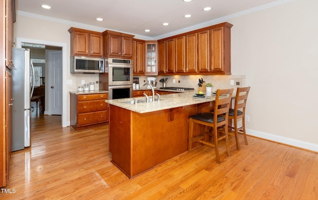 kitchen featuring stainless steel appliances, light hardwood / wood-style floors, sink, and kitchen peninsula