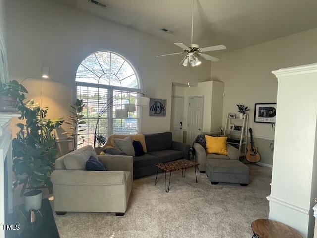 living room with a high ceiling, light colored carpet, visible vents, and ceiling fan