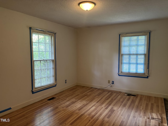spare room featuring wood finished floors, baseboards, and a textured ceiling