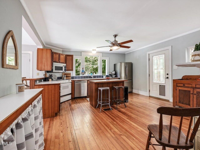 967 Bynum Rd, Pittsboro, NC 27312 - kitchen with stainless steel appliances, a center island, brown cabinets, light wood finished floors, and ceiling fan