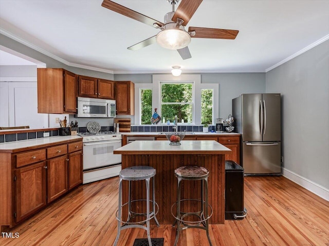 967 Bynum Rd, Pittsboro, NC 27312 - kitchen featuring appliances with stainless steel finishes, light wood-style floors, ornamental molding, a sink, and a breakfast bar area