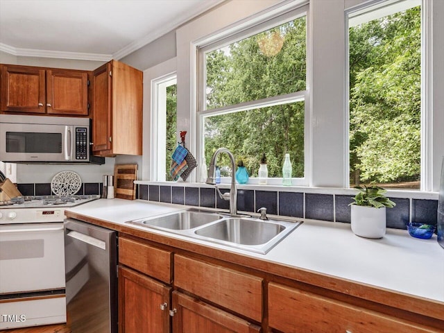 967 Bynum Rd, Pittsboro, NC 27312 - kitchen featuring appliances with stainless steel finishes, a sink, light countertops, brown cabinetry, and crown molding