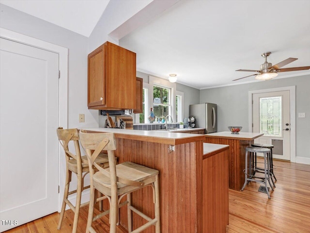 967 Bynum Rd, Pittsboro, NC 27312 - kitchen featuring freestanding refrigerator, brown cabinets, light countertops, a kitchen breakfast bar, and a peninsula