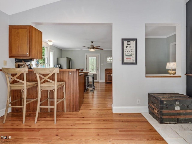 967 Bynum Rd, Pittsboro, NC 27312 - kitchen featuring freestanding refrigerator, light wood-style floors, brown cabinets, a ceiling fan, and a breakfast bar area