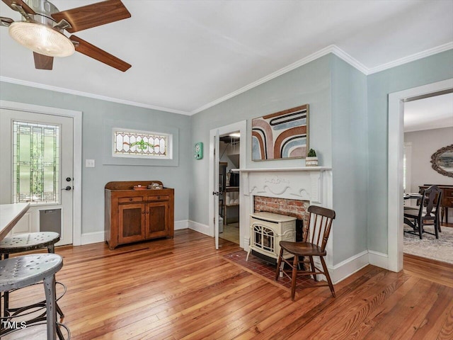 967 Bynum Rd, Pittsboro, NC 27312 - sitting room featuring a wood stove, light wood finished floors, a ceiling fan, crown molding, and baseboards