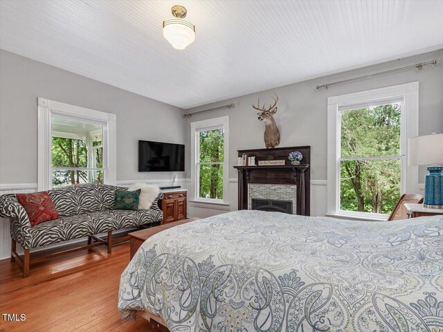 967 Bynum Rd, Pittsboro, NC 27312 - bedroom featuring a wainscoted wall, wood finished floors, multiple windows, a fireplace, and a decorative wall